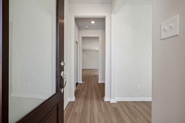 hallway with light wood-style flooring and baseboards