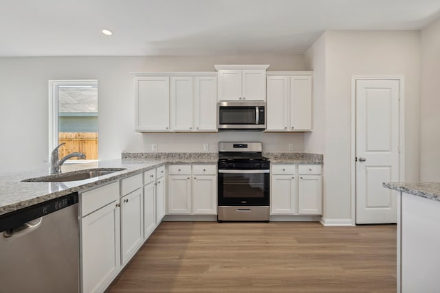 kitchen featuring recessed lighting, a sink, stainless steel appliances, light wood-type flooring, and white cabinetry