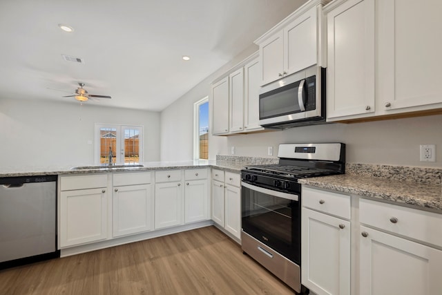kitchen with a sink, visible vents, stainless steel appliances, light wood finished floors, and a ceiling fan