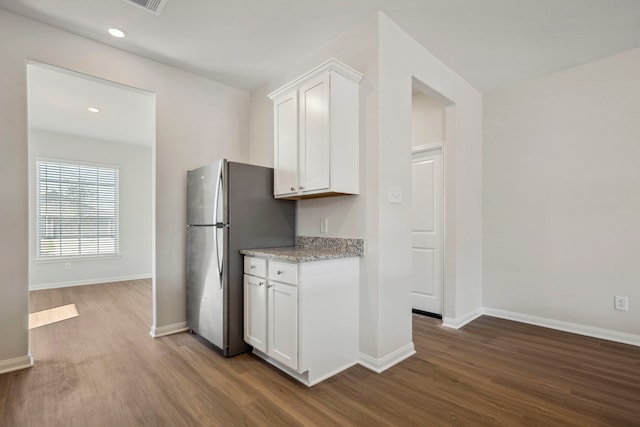 kitchen with white cabinets, freestanding refrigerator, baseboards, dark wood-style flooring, and light stone countertops