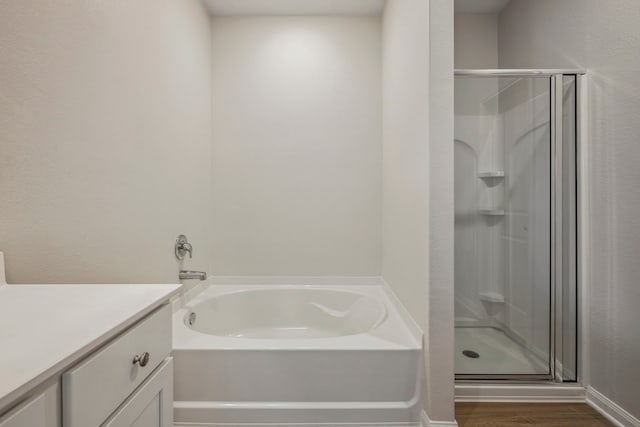 full bathroom with wood finished floors, a shower stall, a bath, and vanity