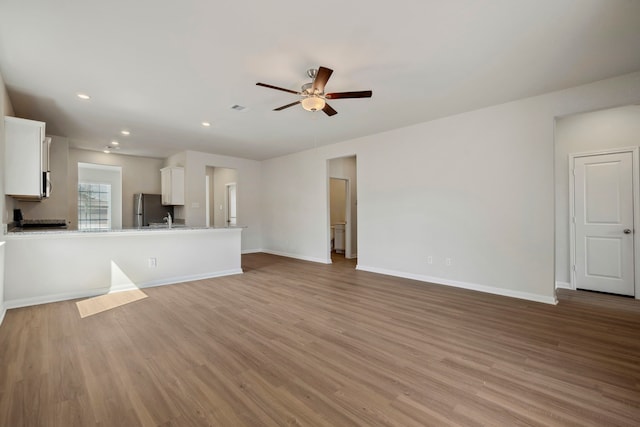 unfurnished living room featuring light wood-style flooring, visible vents, ceiling fan, baseboards, and recessed lighting