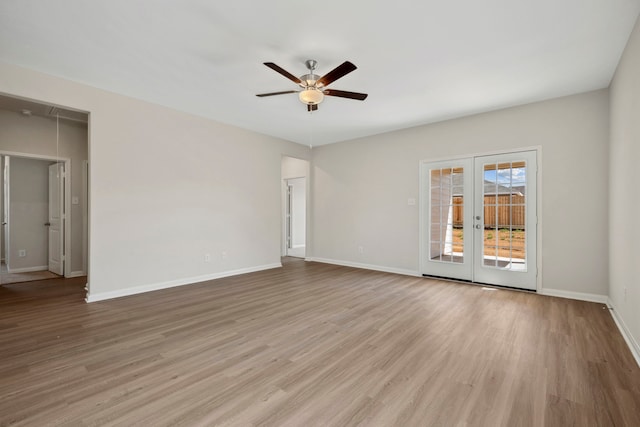 spare room featuring attic access, ceiling fan, wood finished floors, and baseboards