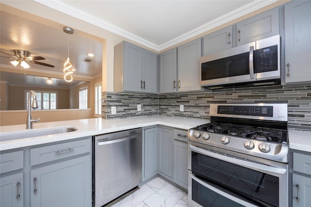 kitchen with crown molding, a sink, appliances with stainless steel finishes, gray cabinetry, and light countertops