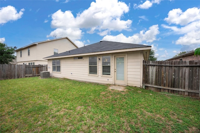 back of property with a lawn, central AC, and a fenced backyard