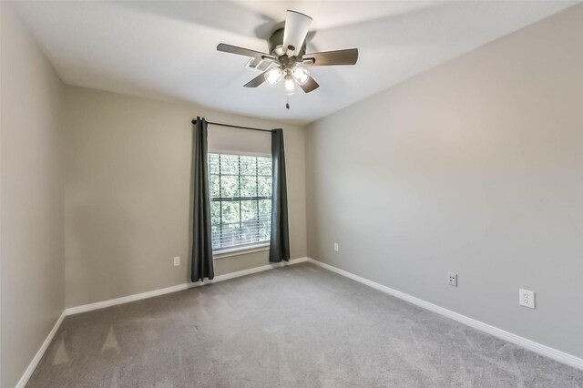 carpeted empty room featuring a ceiling fan and baseboards