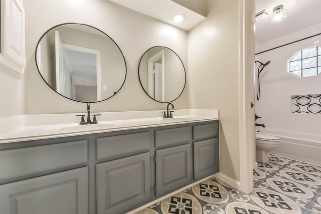 full bath featuring double vanity, shower / tub combination, a sink, tile patterned floors, and toilet
