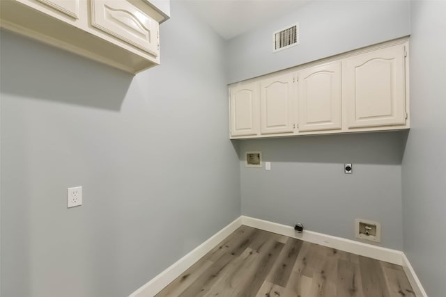 clothes washing area with visible vents, wood finished floors, baseboards, cabinet space, and washer hookup