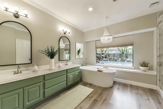 bathroom with crown molding, double vanity, a freestanding bath, and a sink