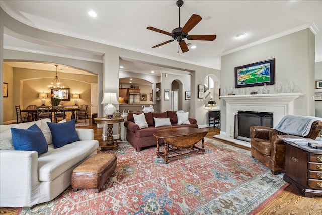 living area featuring crown molding, arched walkways, recessed lighting, and ceiling fan with notable chandelier