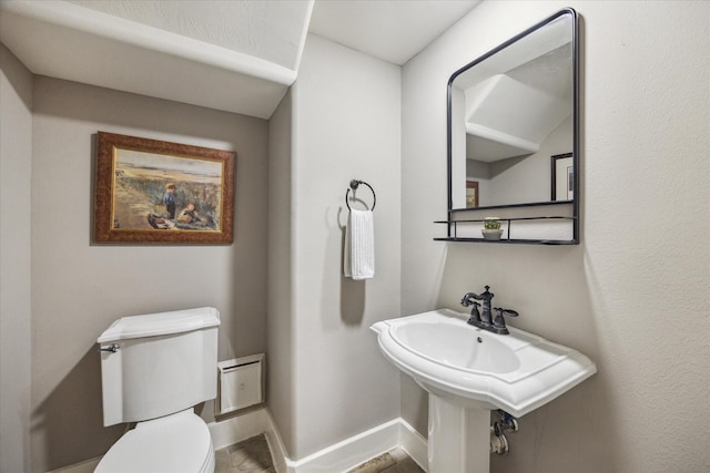 half bathroom featuring toilet and baseboards