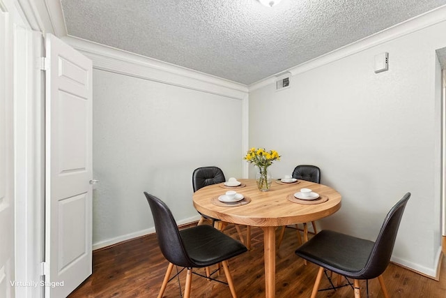 dining room with crown molding, a textured ceiling, dark wood finished floors, and visible vents