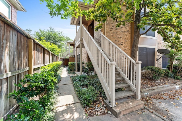 view of home's exterior featuring stairway, brick siding, and fence