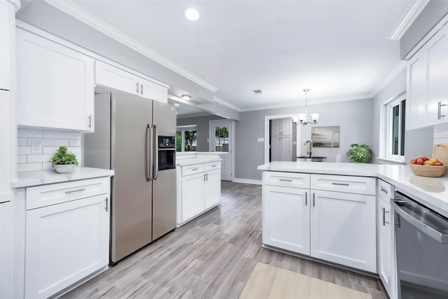 5807 Dumfries Dr, Houston, TX 77096 - kitchen featuring white cabinetry, a chandelier, stainless steel appliances, light countertops, and a peninsula