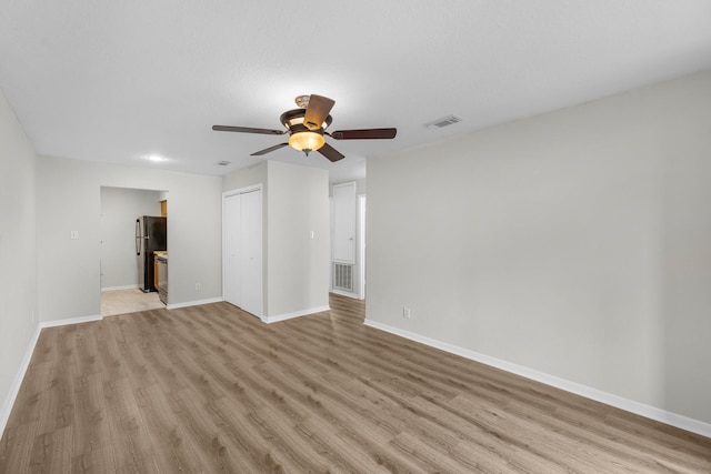 unfurnished living room featuring visible vents, a ceiling fan, light wood finished floors, and baseboards