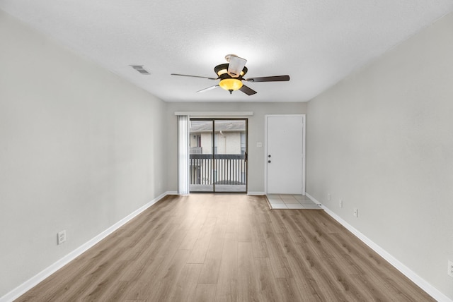 empty room with ceiling fan, visible vents, baseboards, a textured ceiling, and wood finished floors