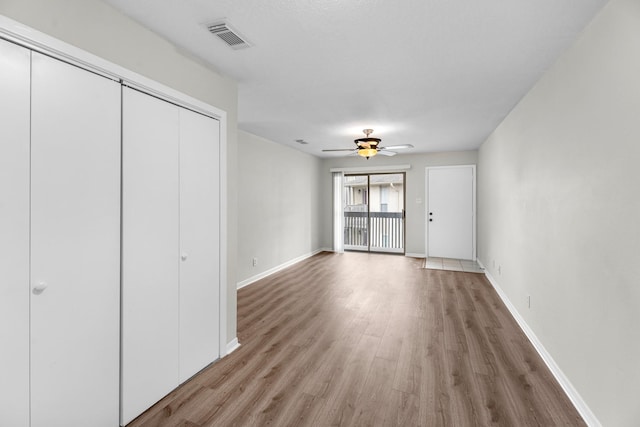 unfurnished living room featuring baseboards, visible vents, a ceiling fan, and light wood-style floors