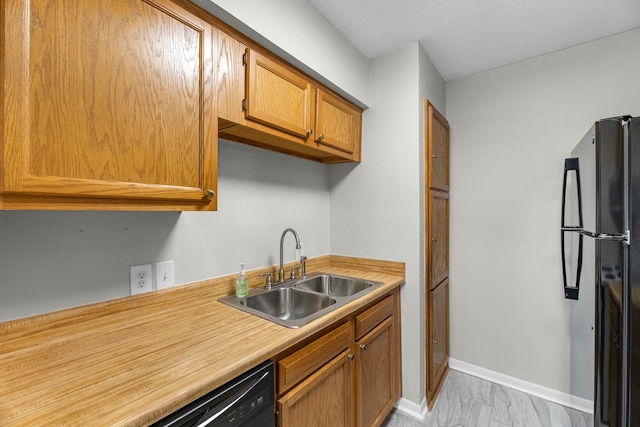 kitchen with freestanding refrigerator, light countertops, marble finish floor, a sink, and baseboards