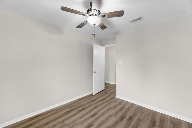 spare room with baseboards, visible vents, wood finished floors, and a ceiling fan