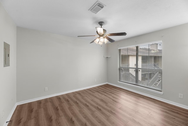 spare room with baseboards, visible vents, wood finished floors, and electric panel