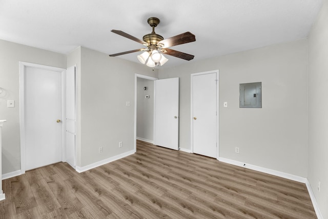 unfurnished bedroom featuring electric panel, ceiling fan, wood finished floors, and baseboards