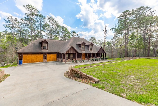 chalet / cabin with a porch, concrete driveway, and a front yard