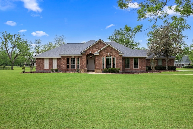 ranch-style home with brick siding, a front lawn, and a shingled roof