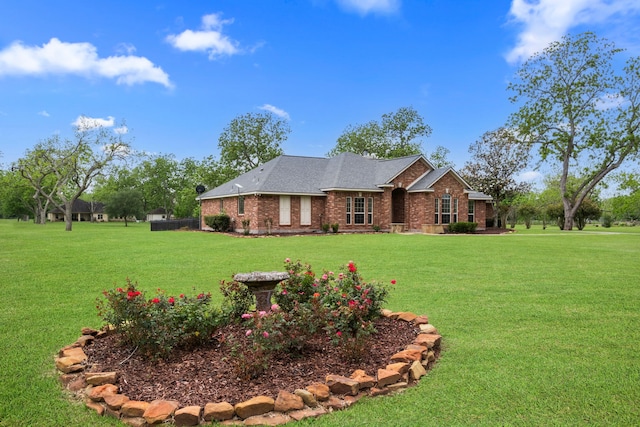ranch-style house with a front yard, roof with shingles, and brick siding