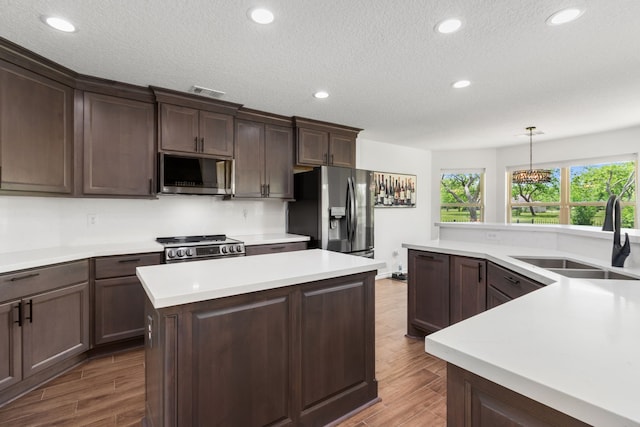 kitchen featuring a center island, appliances with stainless steel finishes, light countertops, and a sink