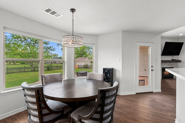 dining area featuring a fireplace, a wealth of natural light, visible vents, and dark wood-type flooring