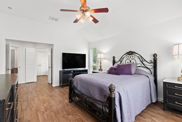 bedroom with ceiling fan, visible vents, vaulted ceiling, baseboards, and wood finished floors