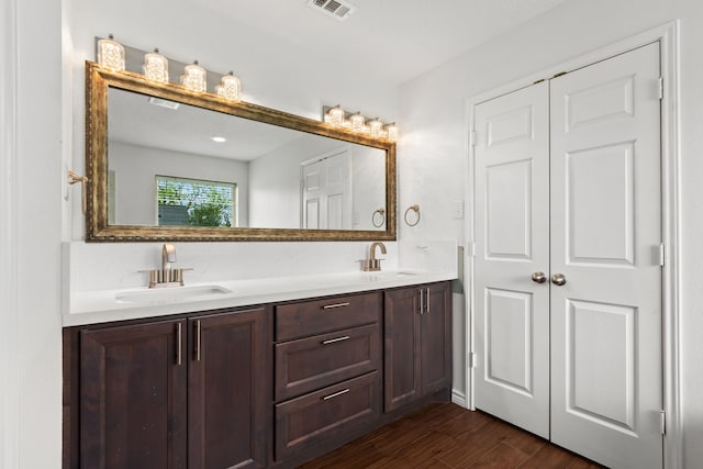 full bathroom with visible vents, wood finished floors, double vanity, and a sink