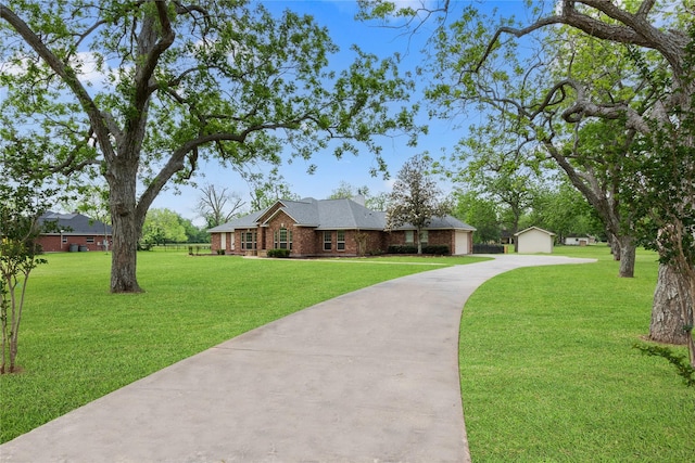 view of front facade featuring an outbuilding, concrete driveway, a front lawn, and brick siding
