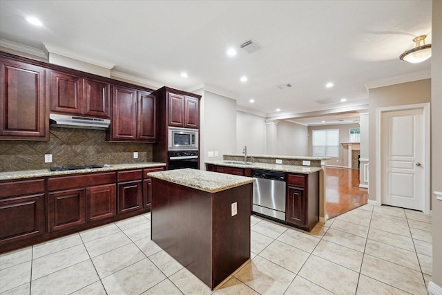 1339 Ella Pl, Houston, TX 77008 - kitchen with appliances with stainless steel finishes, under cabinet range hood, ornamental molding, a kitchen island, and backsplash