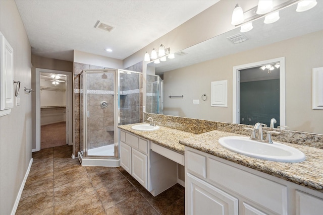 full bath with a stall shower, double vanity, baseboards, and a walk in closet
