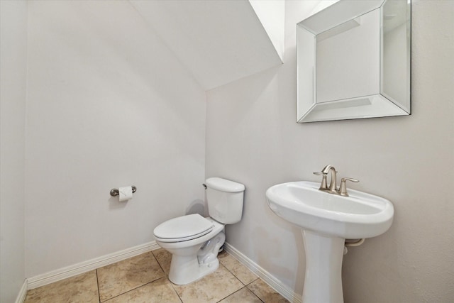 bathroom featuring toilet, tile patterned floors, baseboards, and a sink