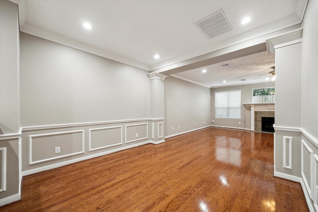 unfurnished living room with crown molding, a tile fireplace, wood finished floors, recessed lighting, and a decorative wall