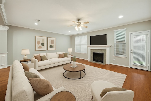 living room featuring a fireplace with flush hearth, ceiling fan, wood finished floors, crown molding, and recessed lighting