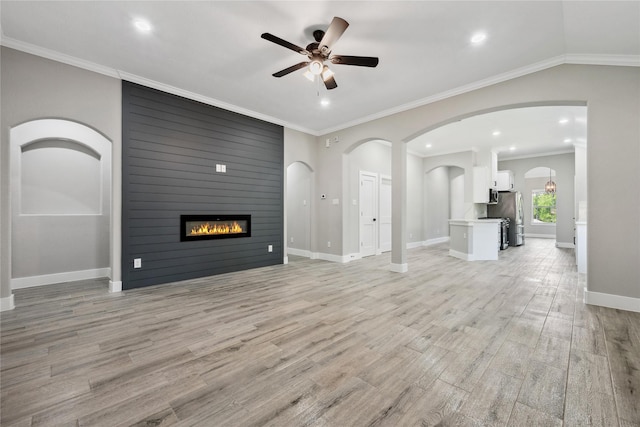 unfurnished living room with a fireplace, ceiling fan, light wood-type flooring, baseboards, and arched walkways