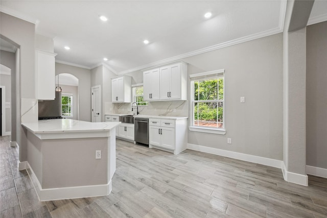 kitchen featuring white cabinetry, stainless steel dishwasher, crown molding, a sink, and arched walkways