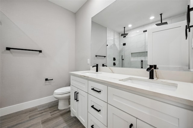 full bath with double vanity, baseboards, a stall shower, and a sink