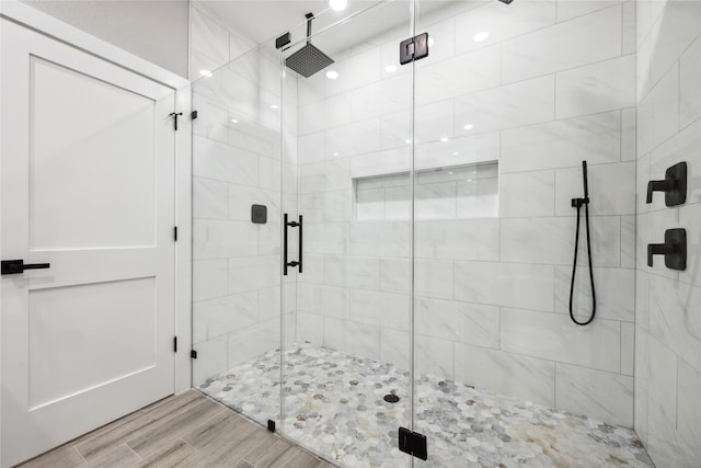 full bath featuring wood finished floors and a shower stall