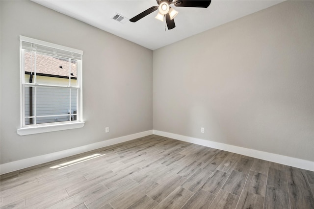 unfurnished room featuring a ceiling fan, visible vents, wood finished floors, and baseboards