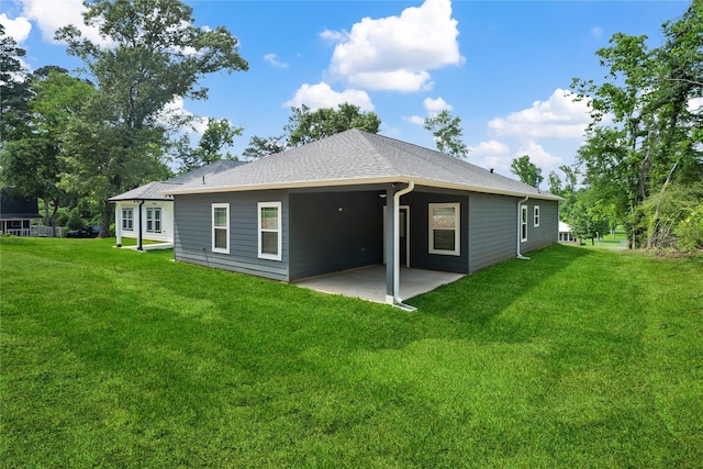 rear view of property with a lawn, a shingled roof, and a patio area