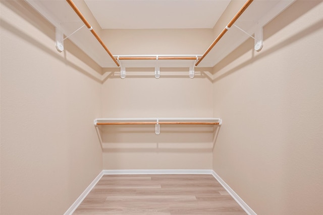 walk in closet with wood finished floors