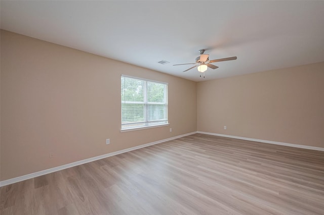 unfurnished room featuring light wood-style floors, a ceiling fan, visible vents, and baseboards