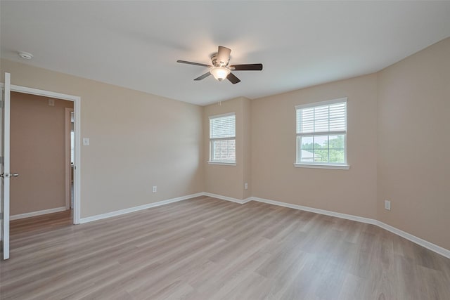 spare room with ceiling fan, baseboards, and light wood-type flooring