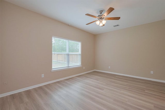 empty room with baseboards, visible vents, ceiling fan, and light wood finished floors