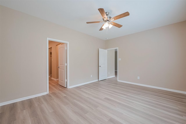 unfurnished bedroom with baseboards, a spacious closet, ceiling fan, and light wood-style flooring