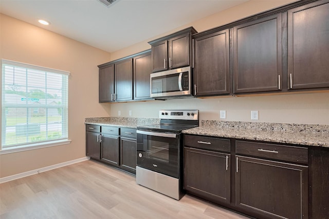 kitchen featuring dark brown cabinetry, light stone counters, stainless steel appliances, and light wood-type flooring